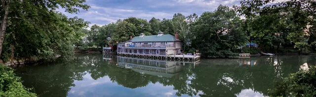 A boat rests on still water surrounded by leafy trees and reflections.