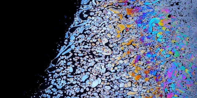 Iridescent blue, yellow, and violet patterns beside a field of tiny bubbles.