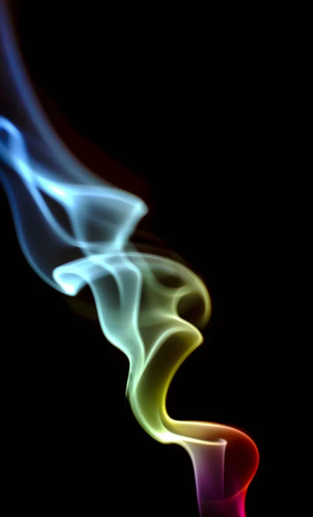 A curling ribbon of smoke shifts from blue to green, yellow, and red against black.