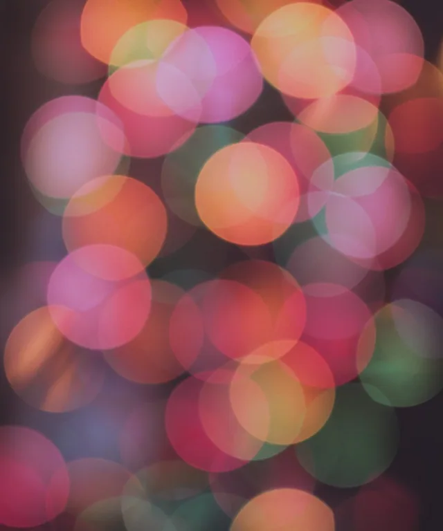 Overlapping circles of pink, orange, green, and yellow light form an abstract blur.