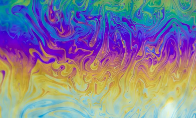 Swirling blue, purple, yellow, and green patterns in an abstract close-up.